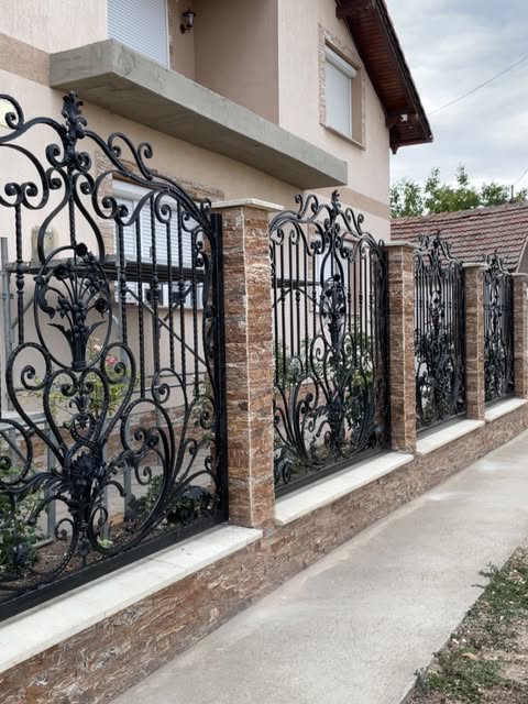 Gard forjat între stâlpi de cărămidă